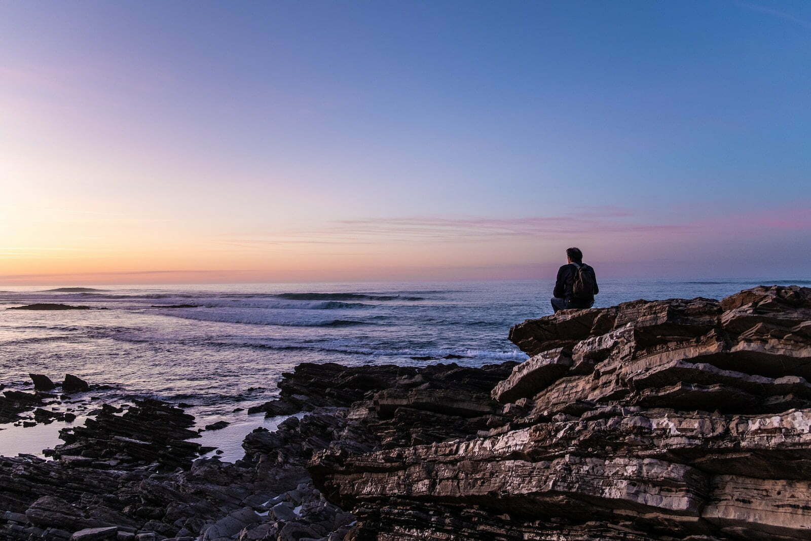 person sitting on cliff alone