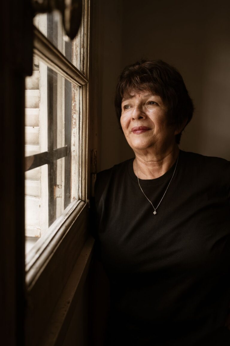 Woman gazing thoughtfully out of a window in soft light