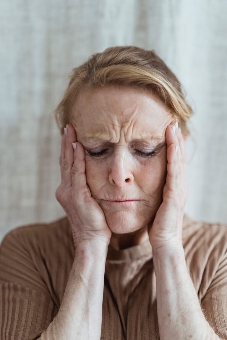 Woman with eyes closed pressing her hands to her temples
