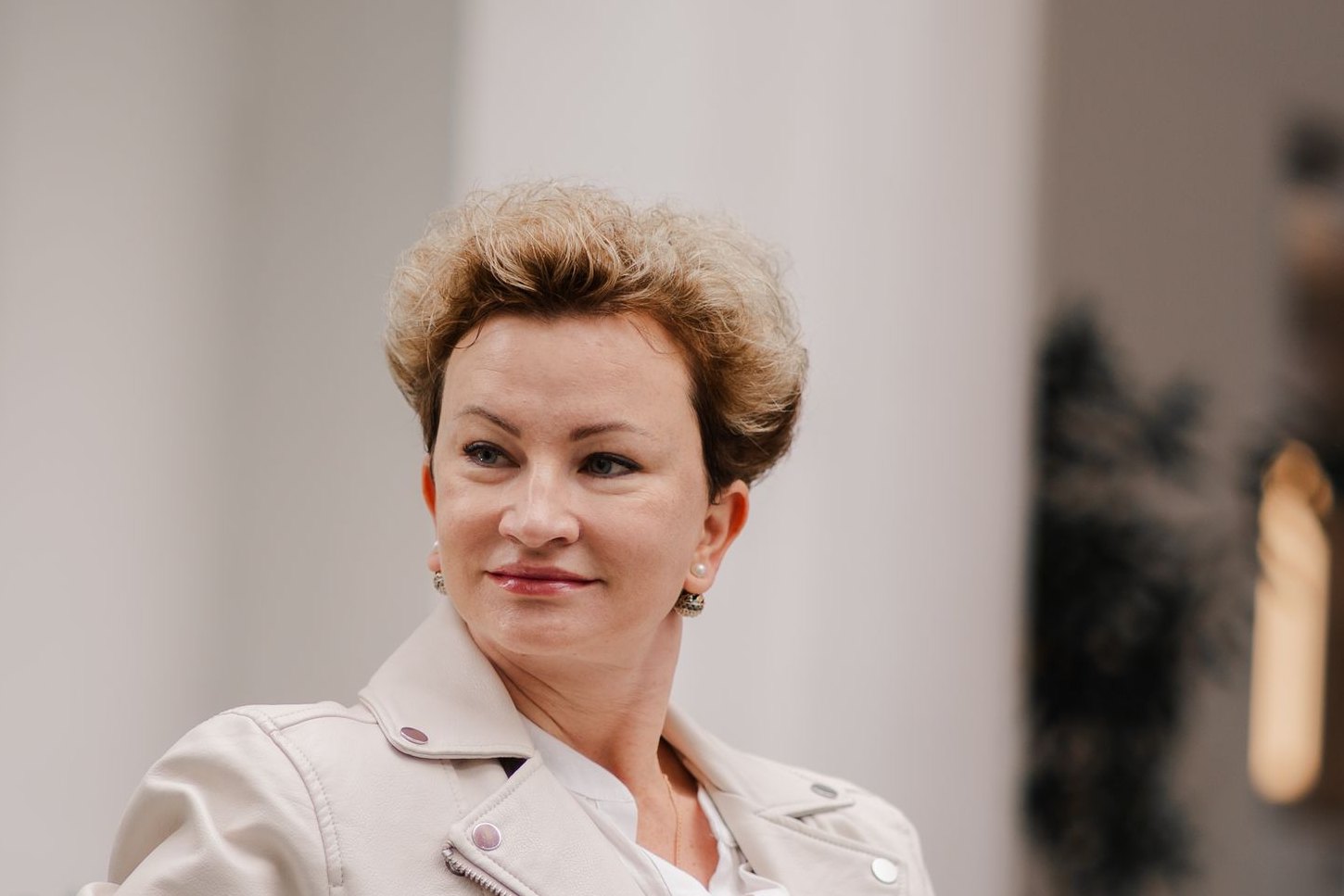 A woman of around fifty with short hair, standing outdoors and looking to one side