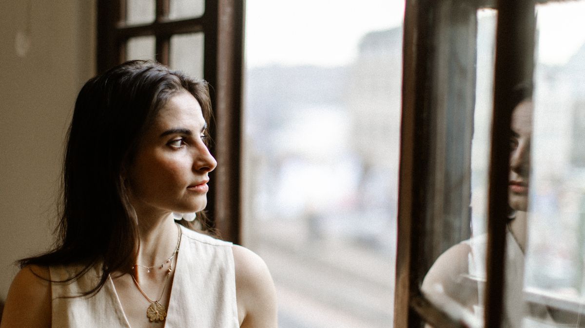 Woman in her thirties looking out of a window in profile
