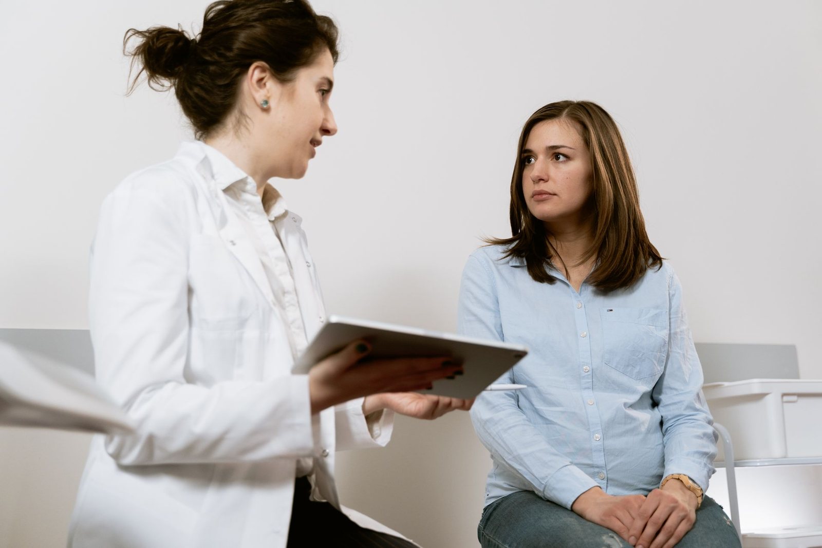 A woman in her thirties listening to a doctor during a consultation