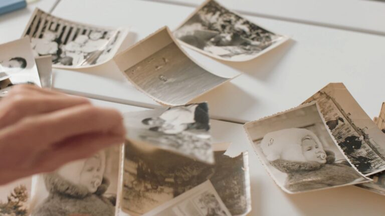 A hand sorting old family photographs on a table